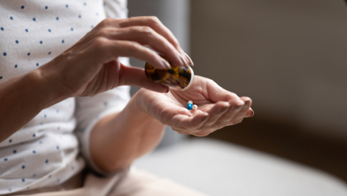 Close-up 60s old woman pours out from bottle pills time to take medicaments.