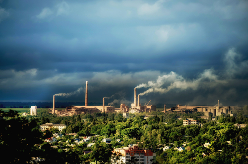 industrial facility located in a residential area with many smoking chimneys.