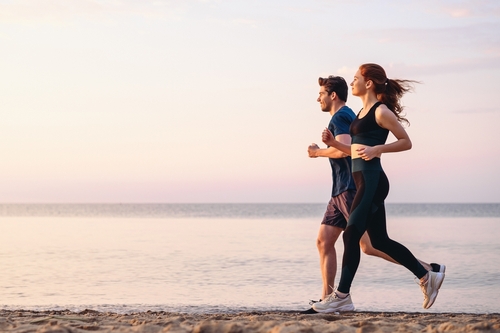 Full body profile couple young two friends training run on sand sea.