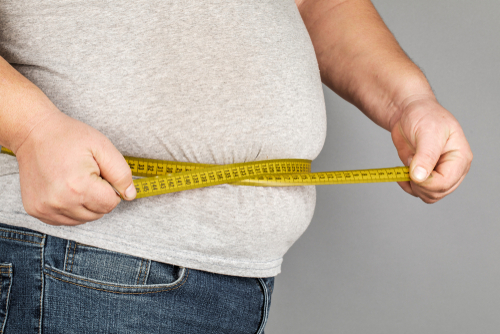 A Man Measures His Fat Belly With A Measuring Tape.