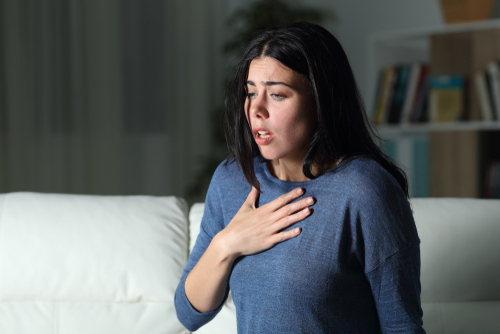 Woman suffering an anxiety attack alone in the night on a couch at home