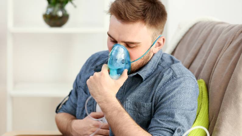 Young man using nebulizer for asthma and respiratory diseases at home