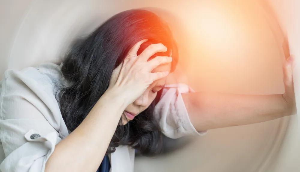 Woman hands on his head felling headache dizzy sense of spinning dizziness,a problem with the inner ear, brain, or sensory nerve pathway.