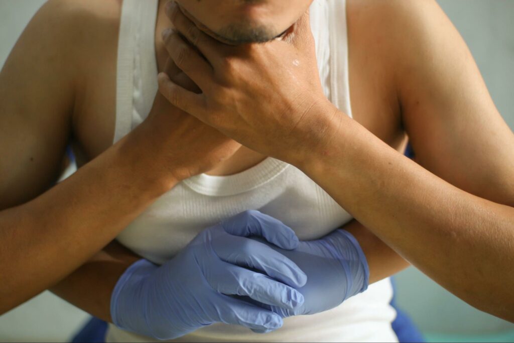 A doctor is performing the Heimlich maneuver on a patient who is choking and has difficulty breathing.