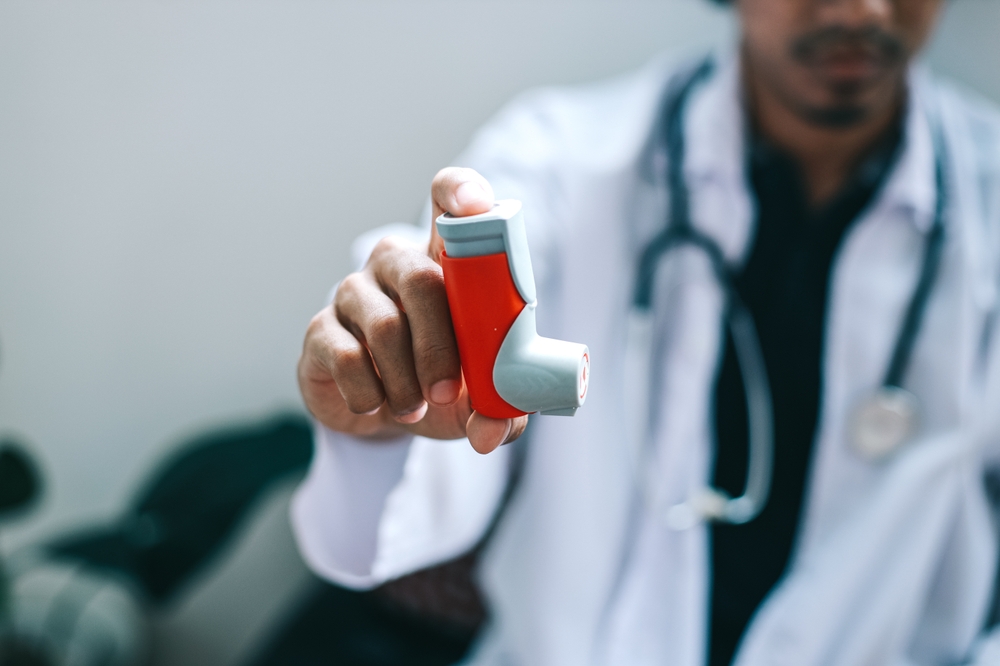 Male Doctor Holding And Showing Asthma Inhaler