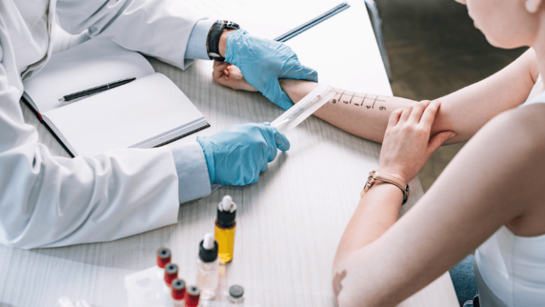 overhead view of allergist holding ruler near marked hand of woman