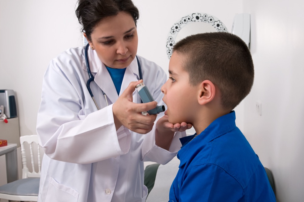 Medical doctor applying oxygen treatment on a little boy with asthma