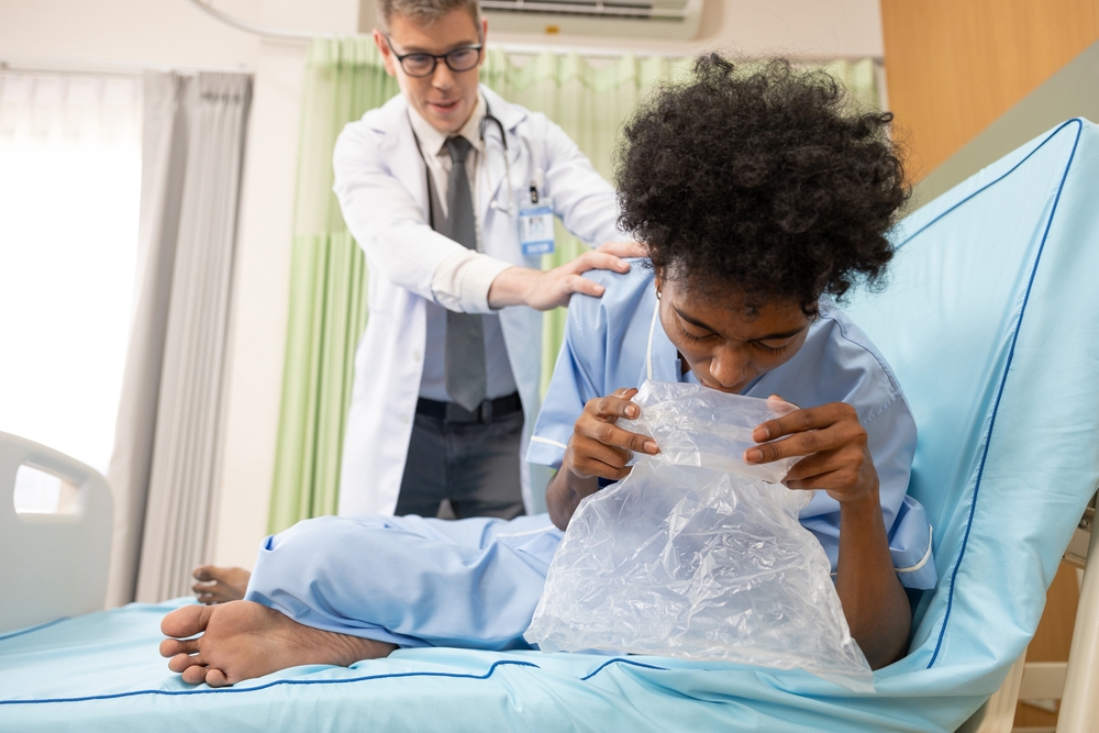 patient vomiting into plastic bag and doctor helping him in hospital