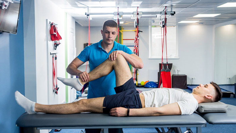 Physiotherapist working with young male patient in the rehabilitation center.